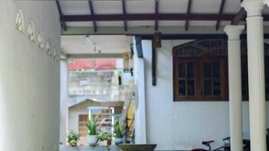 Un espacio al aire libre techado con piso de concreto, una bicicleta y plantas en macetas.