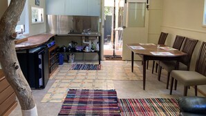 A compact kitchen with a dining area, a tree trunk decoration, and a view through the sliding door. - MOUNTAIN (BALGARR) CABIN RETREAT (Not quite glamping, perfect getaway) (Elands)