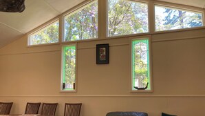 A room with a dining table, chairs, a leather armchair, and large windows with a view of trees. - MOUNTAIN (BALGARR) CABIN RETREAT (Not quite glamping, perfect getaway) (Elands)