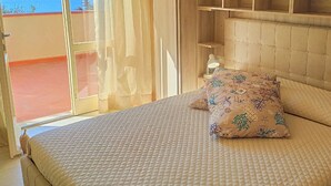Ein Schlafzimmer mit Bett, Nachttisch, Lampe und Meerblick.