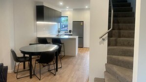 A modern kitchen with a dining area, a refrigerator, and a staircase. - Merivale Executive Stays (Christchurch)
