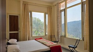 A room with a bed, a chair, and large windows offering a view of the outdoors. - ShantiKunj Homestay Nearby Morni Hills Waterfall (Panchkula)