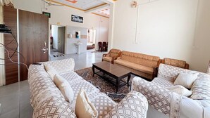 A living room with a sofa set, a coffee table, and a ceiling fan. - ShantiKunj Homestay Nearby Morni Hills Waterfall (Panchkula)