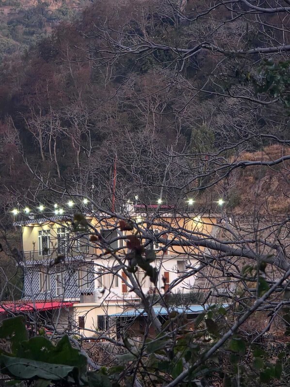 A building with multiple balconies, surrounded by dense foliage and trees.