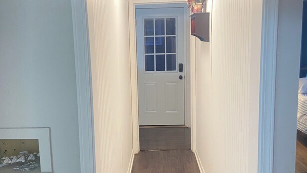 A narrow hallway with a wooden floor, white walls, a door at the end, and a ceiling light fixture. - Spacious 4-bedroom apartment near Mayo Clinic (Rochester)