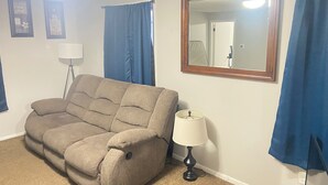 A living room with a sofa, a lamp, a mirror, and blue curtains. - Spacious 4-bedroom apartment near Mayo Clinic (Rochester)