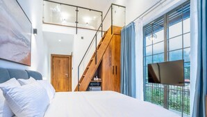 A bedroom with a bed, a TV, a staircase, and a window with a view. - Opulent Villa Nuwara Eliya (Nuwareliya)