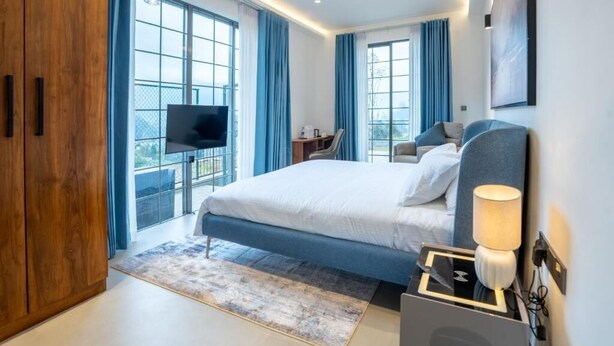 A modern hotel room with a large bed, a desk, a TV, and a balcony with a view. - Opulent Villa Nuwara Eliya (Nuwareliya)