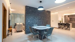 A modern dining area with a round table, chairs, and a stone accent wall. - Opulent Villa Nuwara Eliya (Nuwareliya)