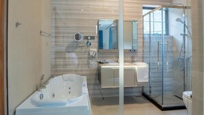 A modern bathroom with a large bathtub, a glass-enclosed shower, and a vanity with a mirror. - Opulent Villa Nuwara Eliya (Nuwareliya)