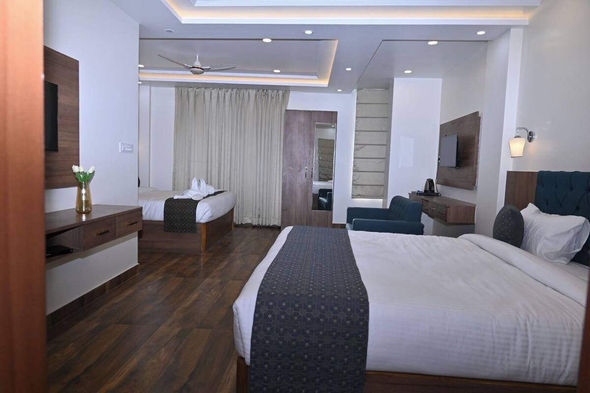 A modern hotel room with a large bed, a desk, a chair, a mirror, and a ceiling fan.