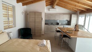 Ein Schlafzimmer mit einem großen Bett, einem Schreibtisch und einer Küchenzeile im Hintergrund.