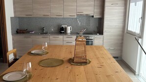 Eine moderne Küche mit Holzschränken, einer Granit Arbeitsplatte und einem Esstisch für vier Personen.