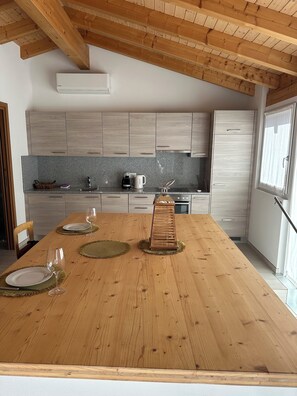A modern kitchen with wooden cabinets, a granite countertop, and a dining table set for four. - Bright studio, just steps to the lake (Ascona)