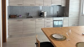 Eine moderne Küche mit hellen Holzschränken, einer Granitarbeitsplatte und einem Holzessttisch mit Glasplatte.