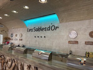 A reception desk with a modern design, a wall with a wavy texture, and a sign that reads 'Les Sables d'Or'. - Vacations Campsite Pirate World Cap Agde (Agde)