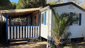 Uma casa móvel pequena e térrea com varanda coberta e área cercada.