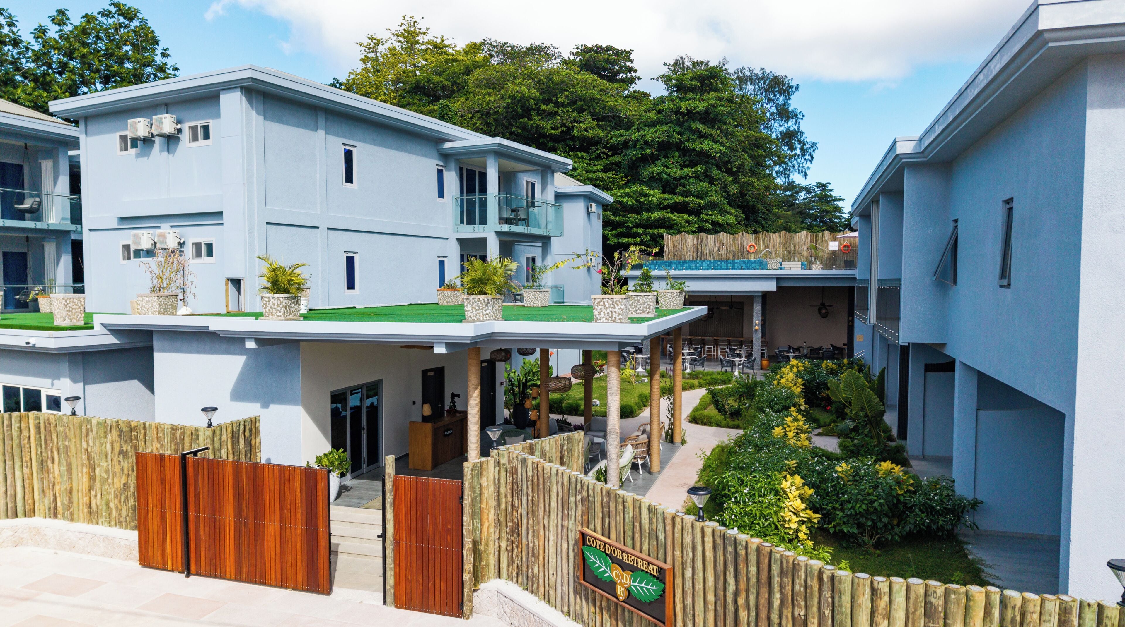 A modern building with multiple levels, outdoor seating, and a wooden fence.