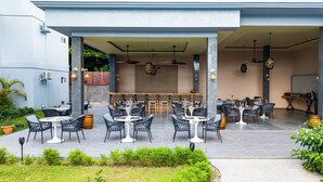 An outdoor dining area with multiple tables and chairs, a bar, and a covered seating area.