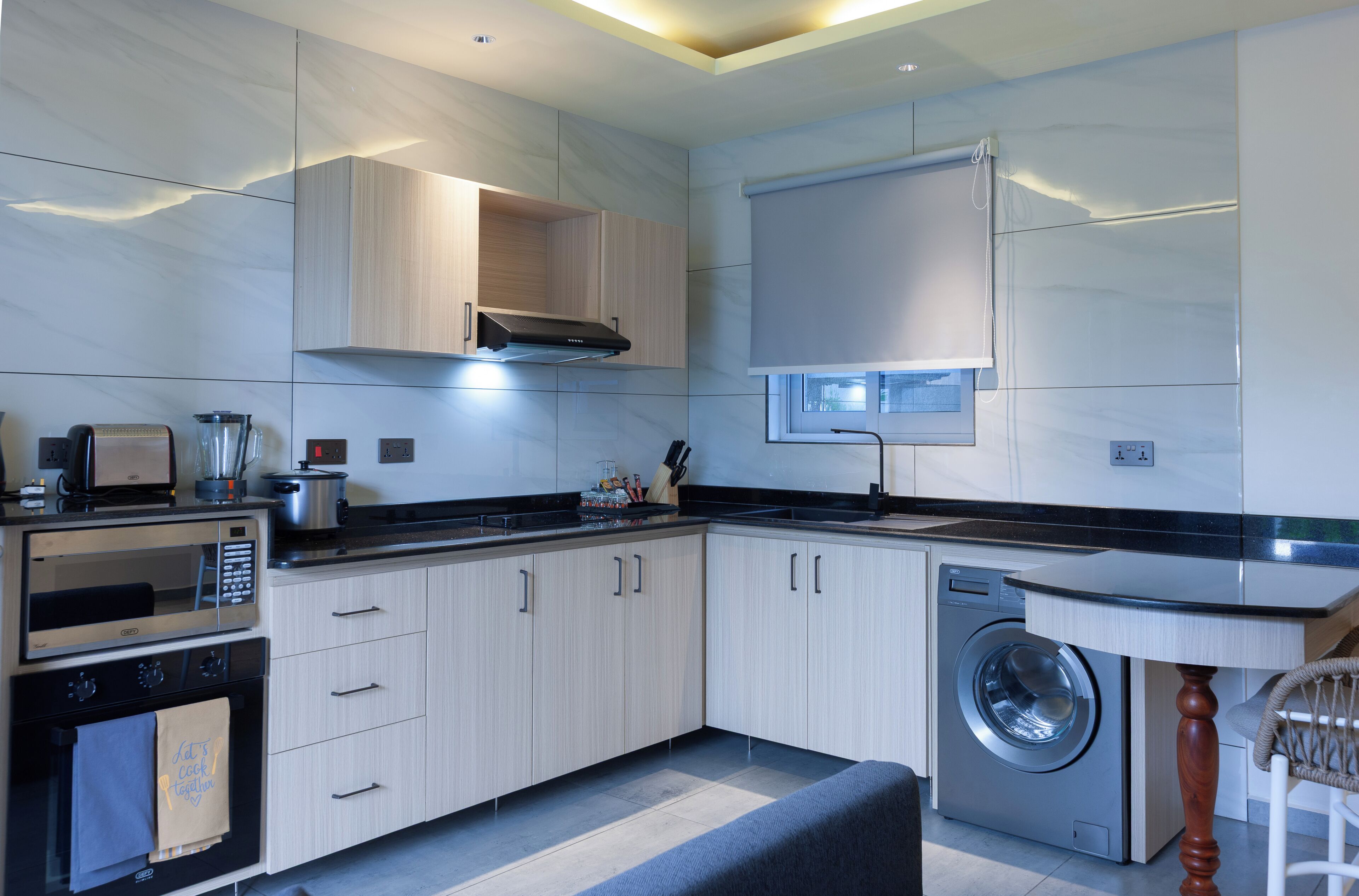 Una cucina moderna con elettrodomestici integrati, una lavatrice e un'area pranzo con tavolo e sedia.