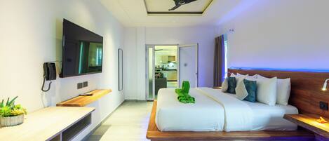 A modern hotel room with a bed, a TV, a ceiling fan, and a small plant on the nightstand.