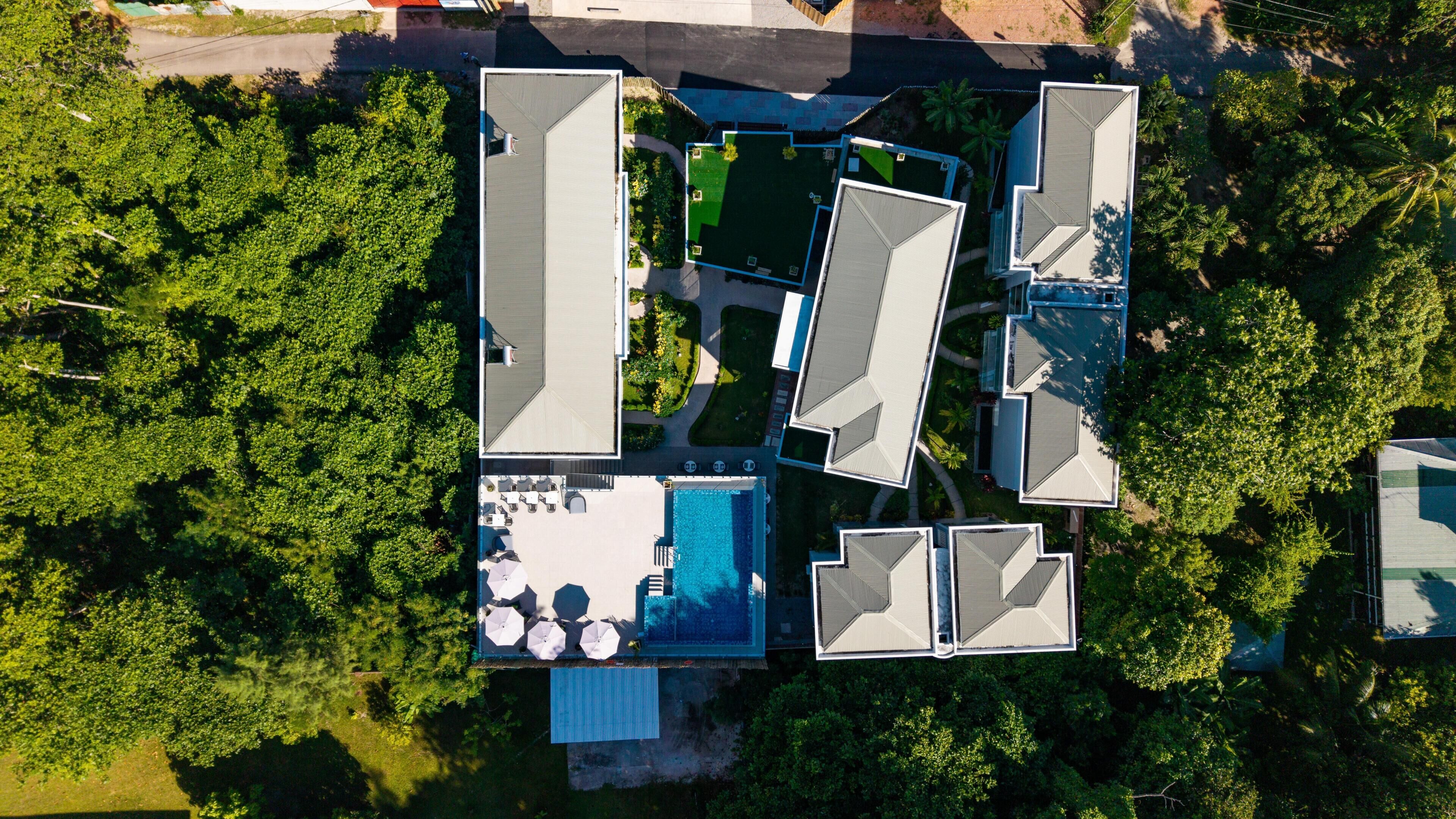 An aerial view of a resort with multiple buildings, a swimming pool, and surrounding greenery.