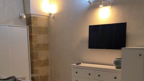 Ein modernes Wohnzimmer mit einer Couch, einem Flachbildfernseher, einem Schrank und Wandleuchten.