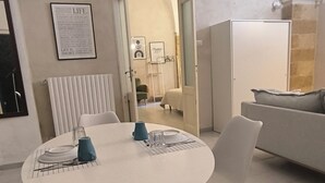 Ein moderner Essbereich mit einem runden Tisch, weißen Stühlen und einer blauen Wasserkaraffe.