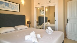Ein Hotelzimmer mit einem Bett, zwei Nachttischen, einem Schrank und einem gerahmten Bild an der Wand.