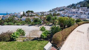 Un pueblo costero con edificios blancos, una playa arenosa y abundante vegetación.