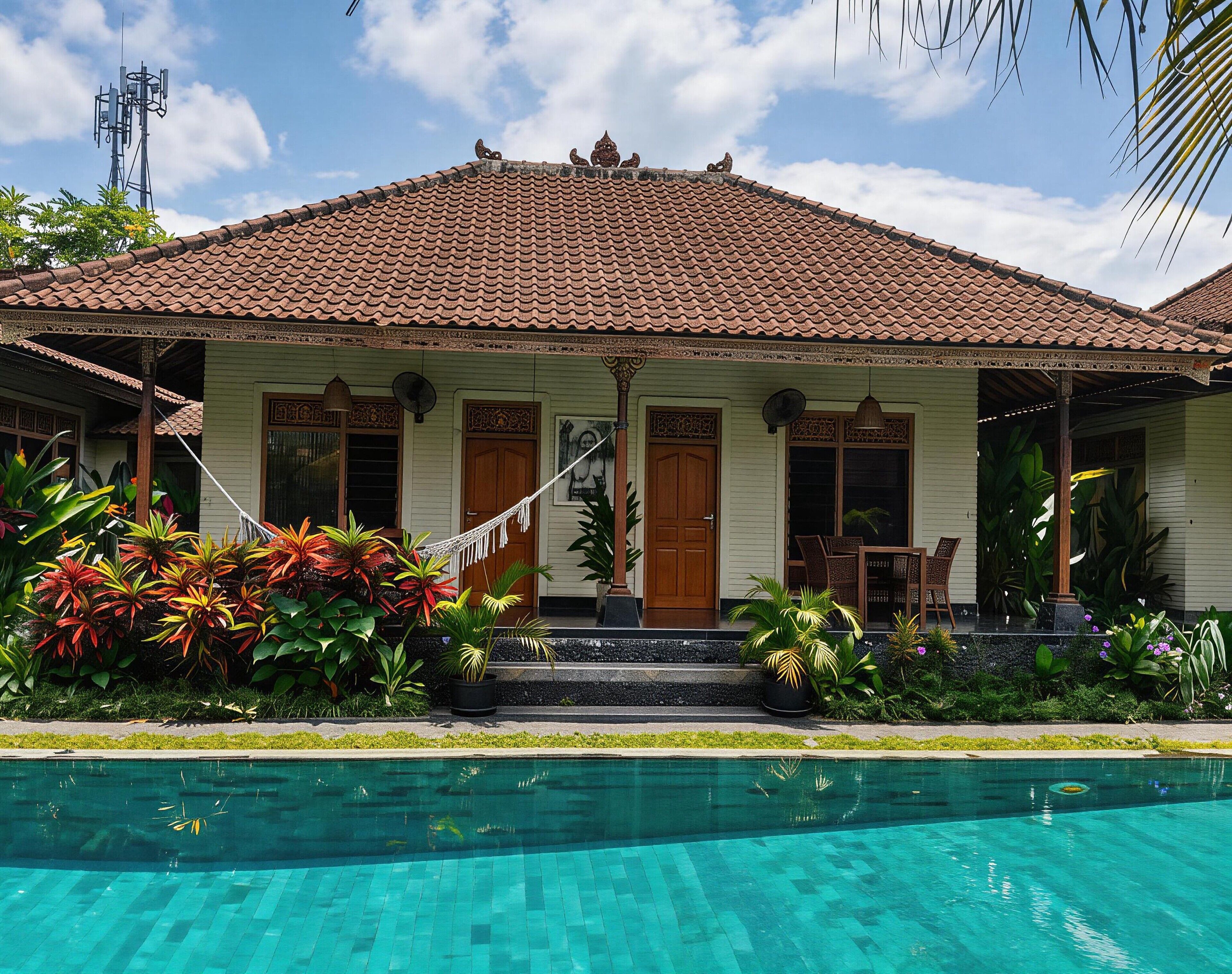 A house with a tiled roof, a front porch with a hammock, and a swimming pool.