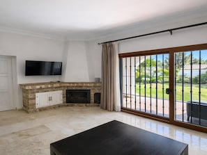 A room with a fireplace, a television, and a sliding glass door leading to an outdoor patio. - Casa Fernando in Estepona (Estepona)