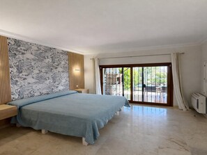 A bedroom with a bed, a wall with a floral pattern, a sliding glass door, and a ceiling fan. - Casa Fernando in Estepona (Estepona)