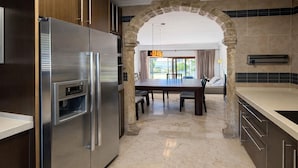 Une cuisine moderne dotée d’un réfrigérateur en acier inoxydable, d’une arche en pierre et d’un coin repas avec une table et des chaises.