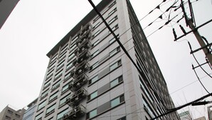 Un edificio de varios pisos con escaparate que dice 'CU' y un toldo morado.