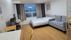 Una habitación de hotel con una cama, un sofá, un escritorio y una silla.