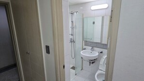 Un baño con cabina de ducha de vidrio, lavabo e inodoro.