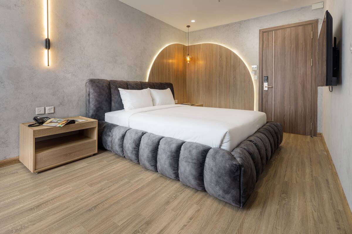 Une chambre à coucher moderne avec un lit, une table de chevet et un téléviseur fixé au mur.
