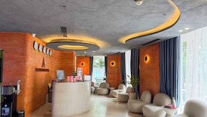 Un hall d’hôtel comprenant un comptoir d’accueil, un espace salon et de grandes fenêtres.