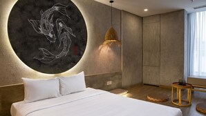 Une chambre à coucher moderne avec un grand lit, une œuvre d’art murale de forme circulaire, une suspension et une table ronde en bois.