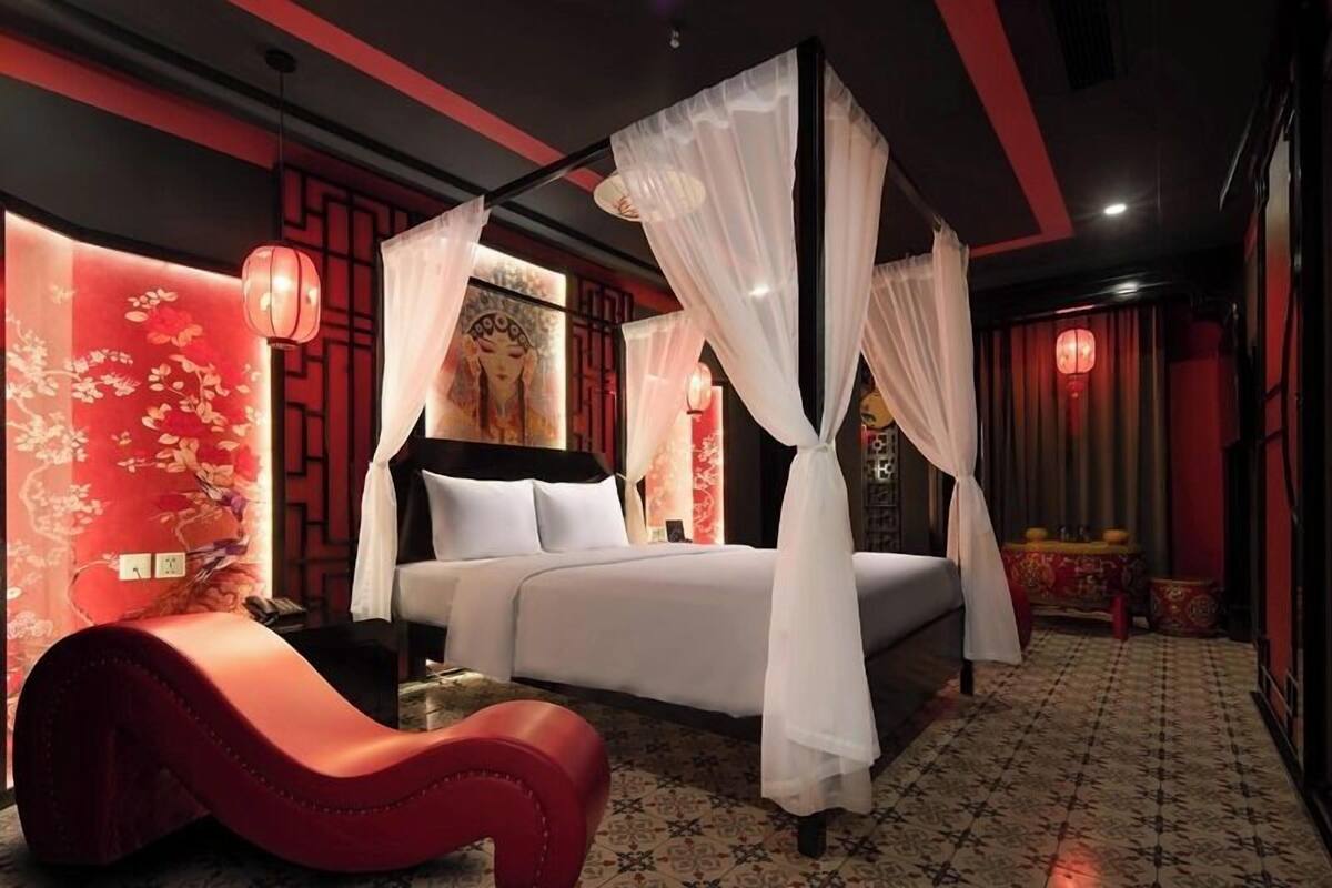 Une chambre à coucher avec un lit à baldaquin, un fauteuil rouge et un décor traditionnel.