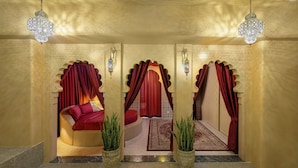 Une chambre luxueuse avec un lit à la forme arrondie, des rideaux rouges et des luminaires décoratifs.
