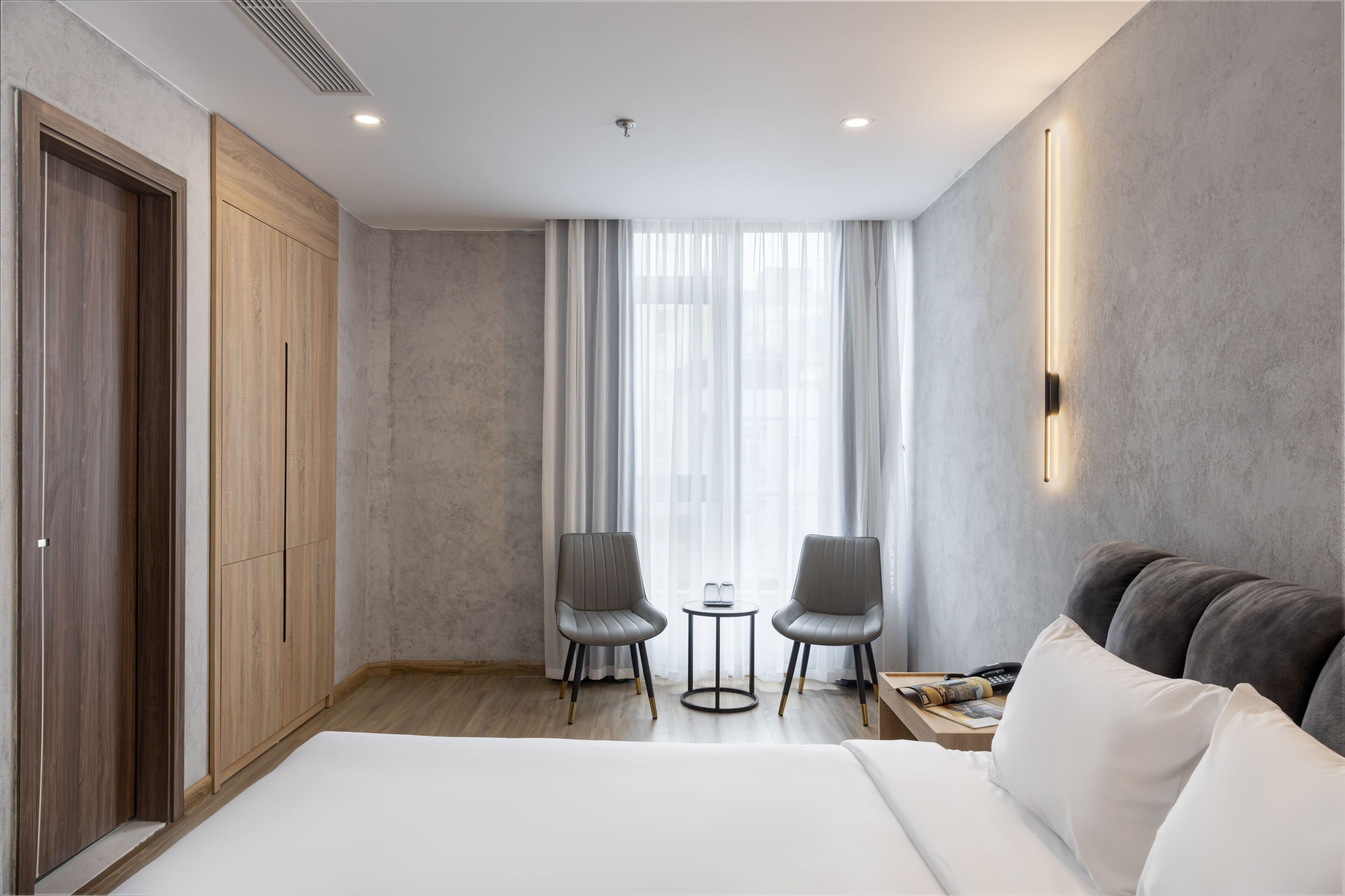 A hotel room with a large bed, two chairs, a small table, and a sofa.
