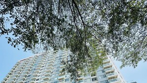 Un edificio de varios pisos con balcones, un letrero que dice 'NERA GARDEN 2' y varios coches estacionados.