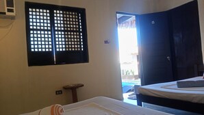 Una habitación de hotel con una cama, una ventana de diseño cuadriculado, una puerta y un aire acondicionado instalado en la pared.