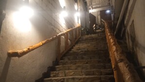 Una escalera de piedra con barandales, que lleva a la entrada de un edificio de noche.