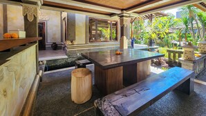 A modern interior with a central island, seating, and a view of tropical plants. - Villa Hibiscus Sanur by Nagisa Bali (Denpasar)