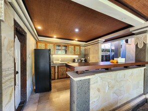 Una cocina con encimera de mármol, refrigerador negro y armarios de madera decorativos.