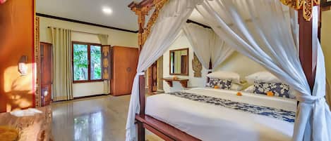 Una habitación amplia con una cama grande, un armario de madera y una ventana con cortinas.