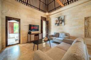 A modern living room with a sofa, coffee table, and a TV mounted on the wall. - Villa Hibiscus Sanur by Nagisa Bali (Denpasar)